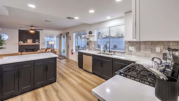 A modern kitchen with dark cabinetry, a central island, and a large window providing natural light. - Entertainment Galore in 4BR Oasis w/ Pool! (North Las Vegas)