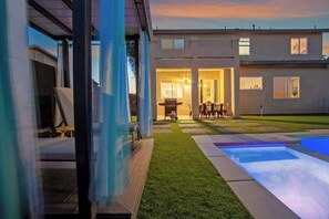Een modern huis met een verzorgd gazon, een zwembad en een patio met buitenmeubilair.