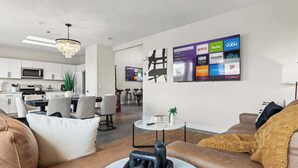 Un salon moderne avec un canapé, une table basse et un mur dédié à la télévision, sur lequel sont affichés les services de diffusion en continu.