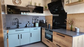 A modern kitchen with grey cabinets, a black stove, and a wooden countertop.
