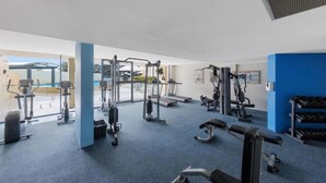 Une salle de sport équipée de divers appareils d’exercice, notamment des tapis de course, des appareils de musculation et des poids libres.