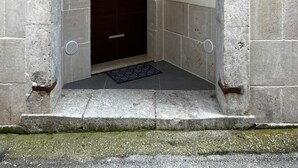 A stone entrance with a dark wooden door, a small window, and a number '30' sign above. - Z-y-x- Residence Archive 180 (Cesinali)