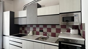 A modern kitchen with a herringbone-patterned floor, a built-in microwave, and a stainless steel sink. - Z-y-x- Residence Archive 180 (Cesinali)