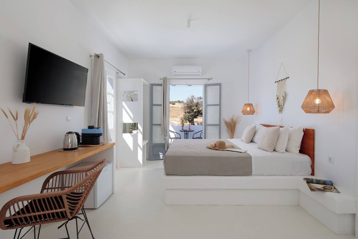 A modern bedroom with a bed, a desk, a chair, and a TV.