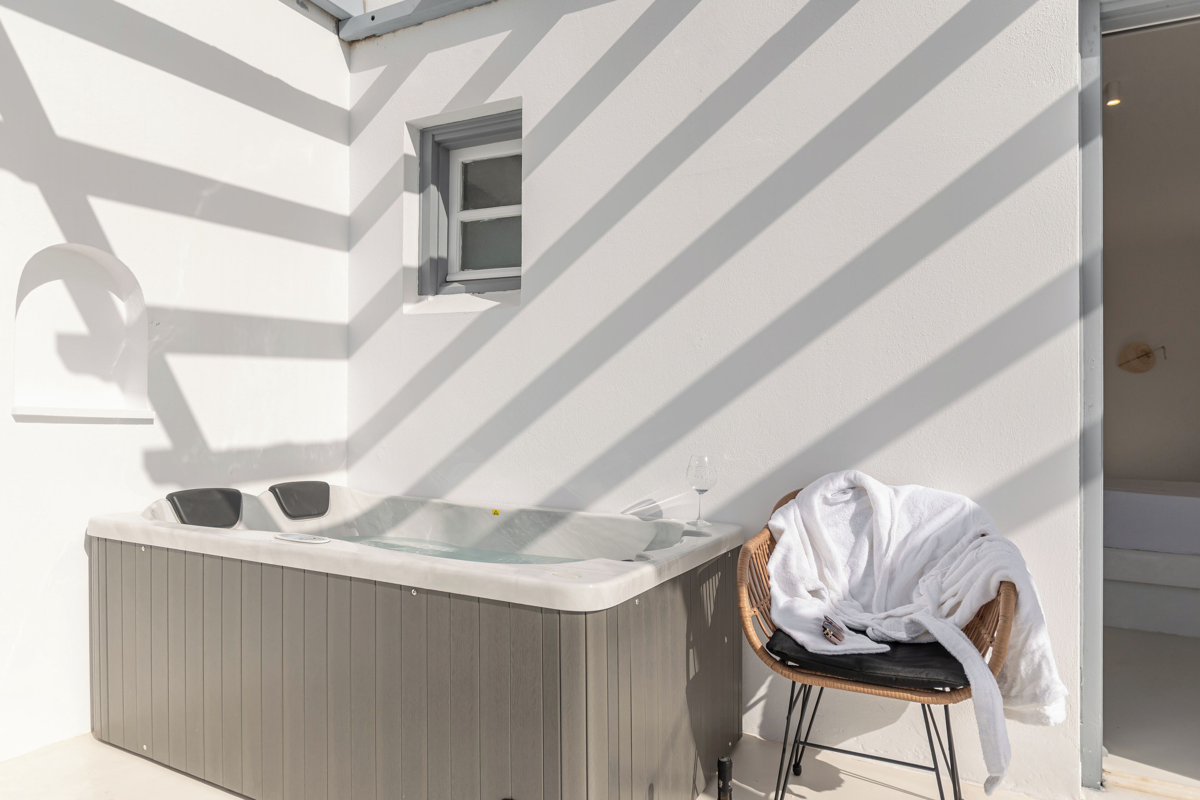 Ein moderner Außenbereich mit Whirlpool, einem Holzstuhl und einem Handtuch.