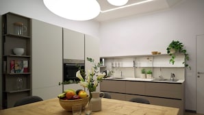 Una cocina moderna con una mesa de comedor de madera, un cuenco de fruta y un florero con flores.