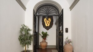 Un pasillo con un amplio arco de entrada, dos plantas en macetas y un adorno de pared.