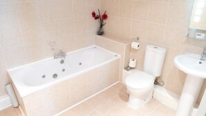 A bathroom with a bathtub, toilet, and sink, all in white. - Cambridge Hotel Waterfront (Brighouse)