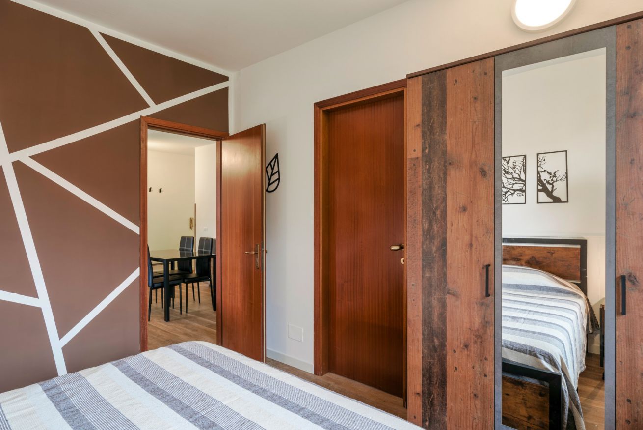 Un dormitorio con cama, un armario de madera y una puerta que da a un comedor.