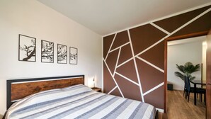 A bedroom with a bed, a wall with geometric patterns, and a dining area visible through an open door. - Moretto 11. with pool and WiFi (Sirmione)