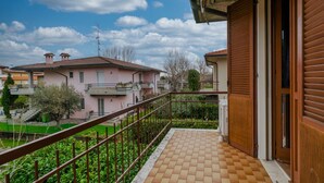 A balcony with a tiled floor, a metal railing, and a view of neighboring houses. - Moretto 11. with pool and WiFi (Sirmione)
