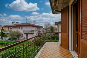 A balcony with a tiled floor, a metal railing, and a view of neighboring houses.