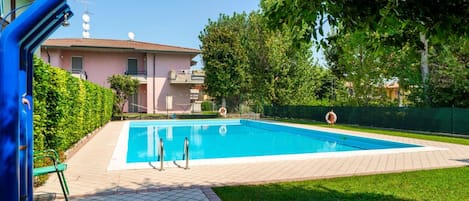 A swimming pool with a tiled deck, a small diving area, and a lifebuoy.