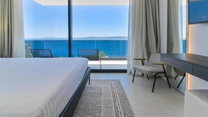 Un hotel moderno con una cama grande, un escritorio y vista al mar.
