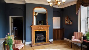 A room with a fireplace, a mirror, a striped chair, and a wooden cabinet. - Hadley Park House Hotel (Telford)