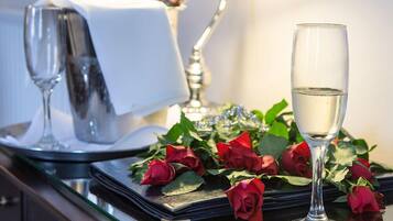 A table with a glass of water, a folded napkin, a silver pitcher, and a bouquet of red roses.