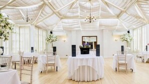 A spacious hall with high ceilings and natural light, featuring tables and chairs arranged for events. - Hadley Park House Hotel (Telford)