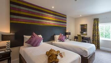 A hotel room with two beds, a large abstract painting on the wall, a desk with a chair, a mirror, and a window with curtains.