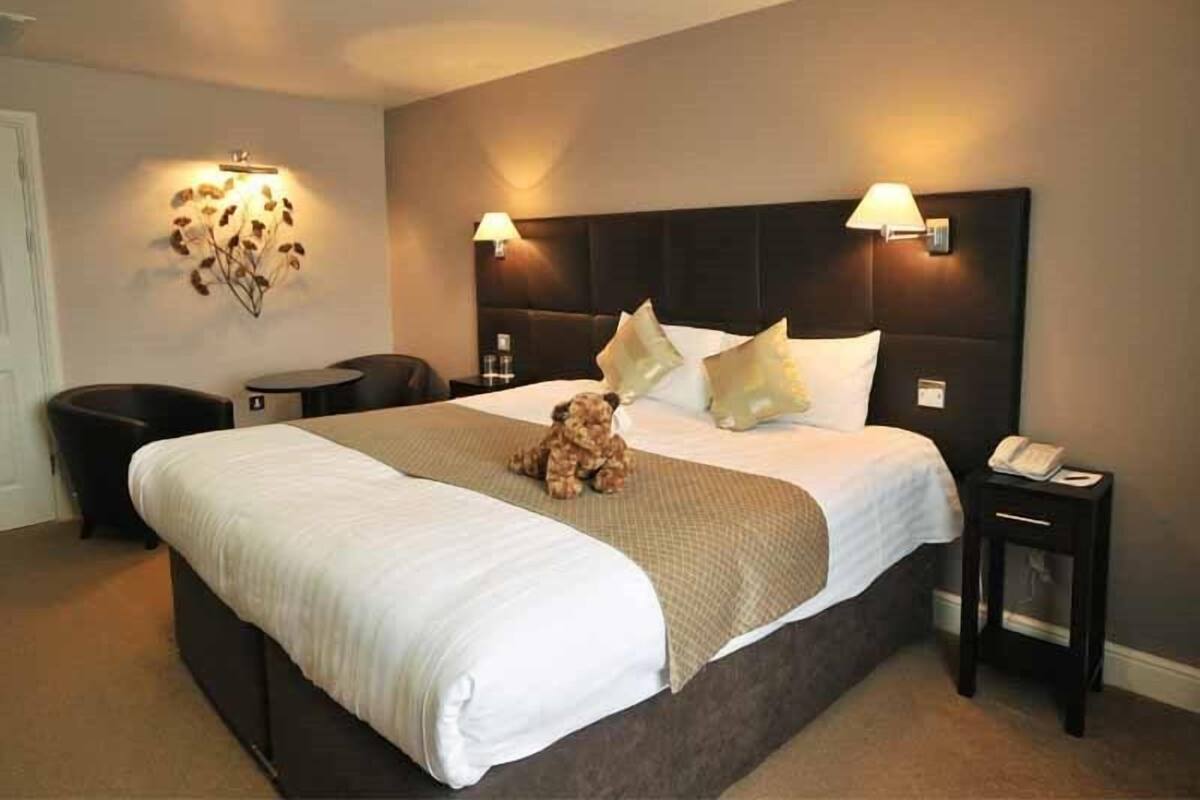 Een hotelkamer met een groot bed, twee bedlampjes, een kleine tafel en een stoel.