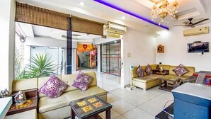 A modern hotel lobby with a seating area, a reception desk, and a television. - Hotel City Pride (Haridwar)