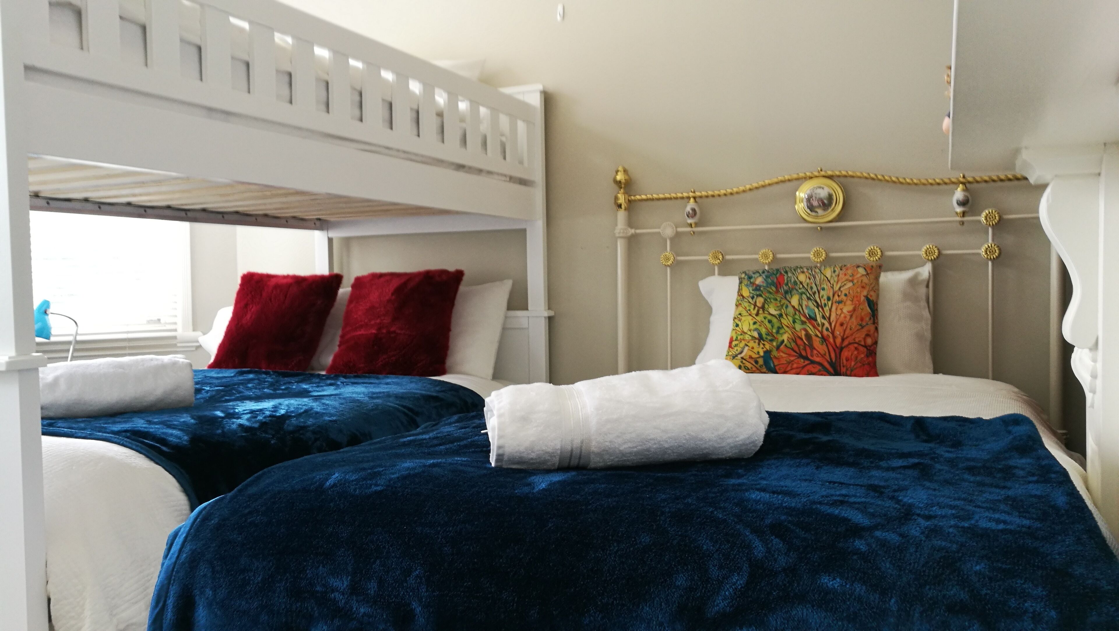 A double bed with a headboard, two pillows, a blanket, and a window with a view.