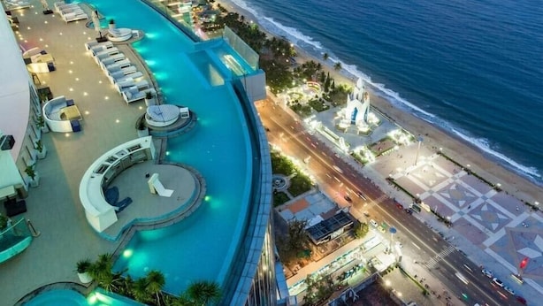 A resort with a pool area, a beach, and a promenade.