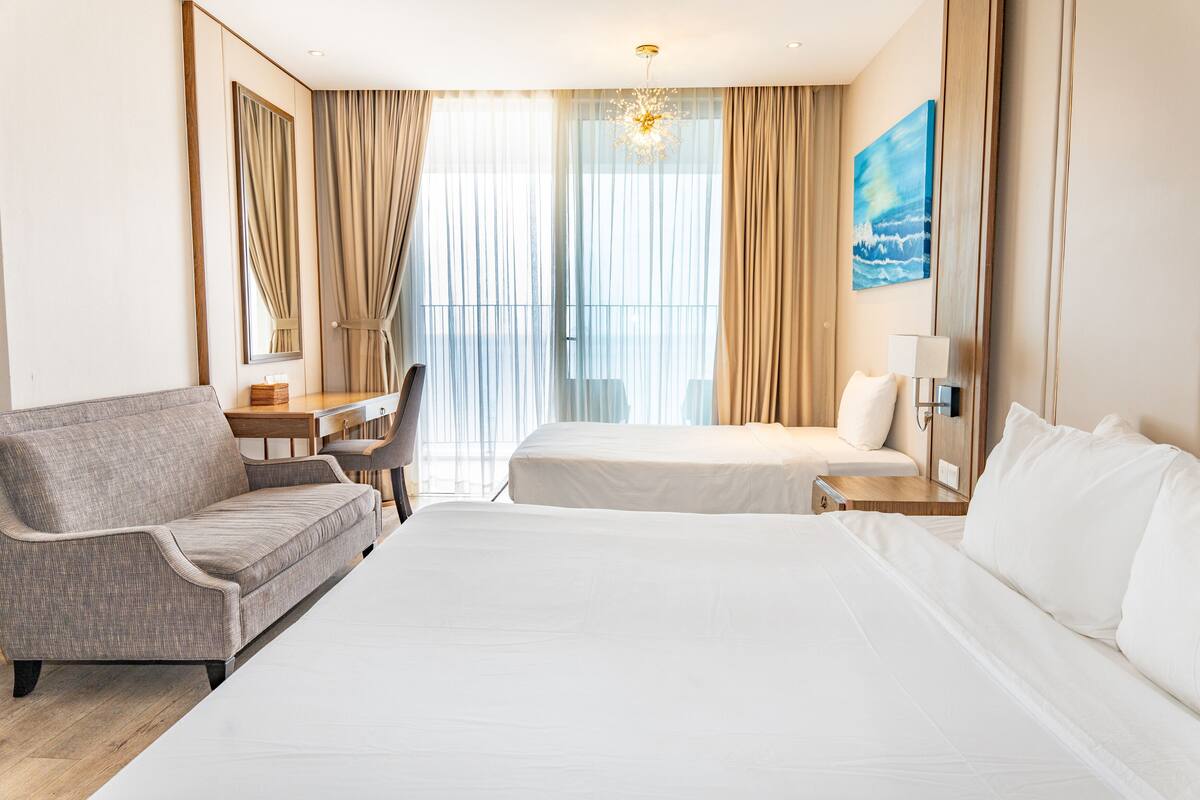 A hotel room with a large bed, a sofa, a desk, and a chair.