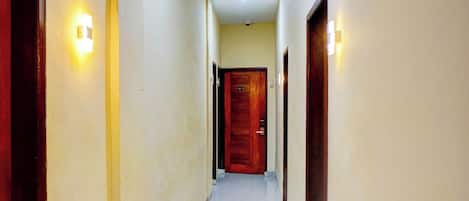 A hallway with wooden doors, numbered 205, and wall-mounted light fixtures.