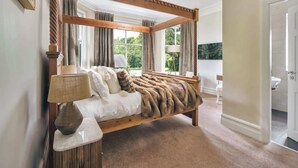 A four-poster bed with a fur throw, a vase, and a lamp on a marble nightstand. - Rosemount Lakes Townhouse with Hot Tub | Ridgestone (Windermere)