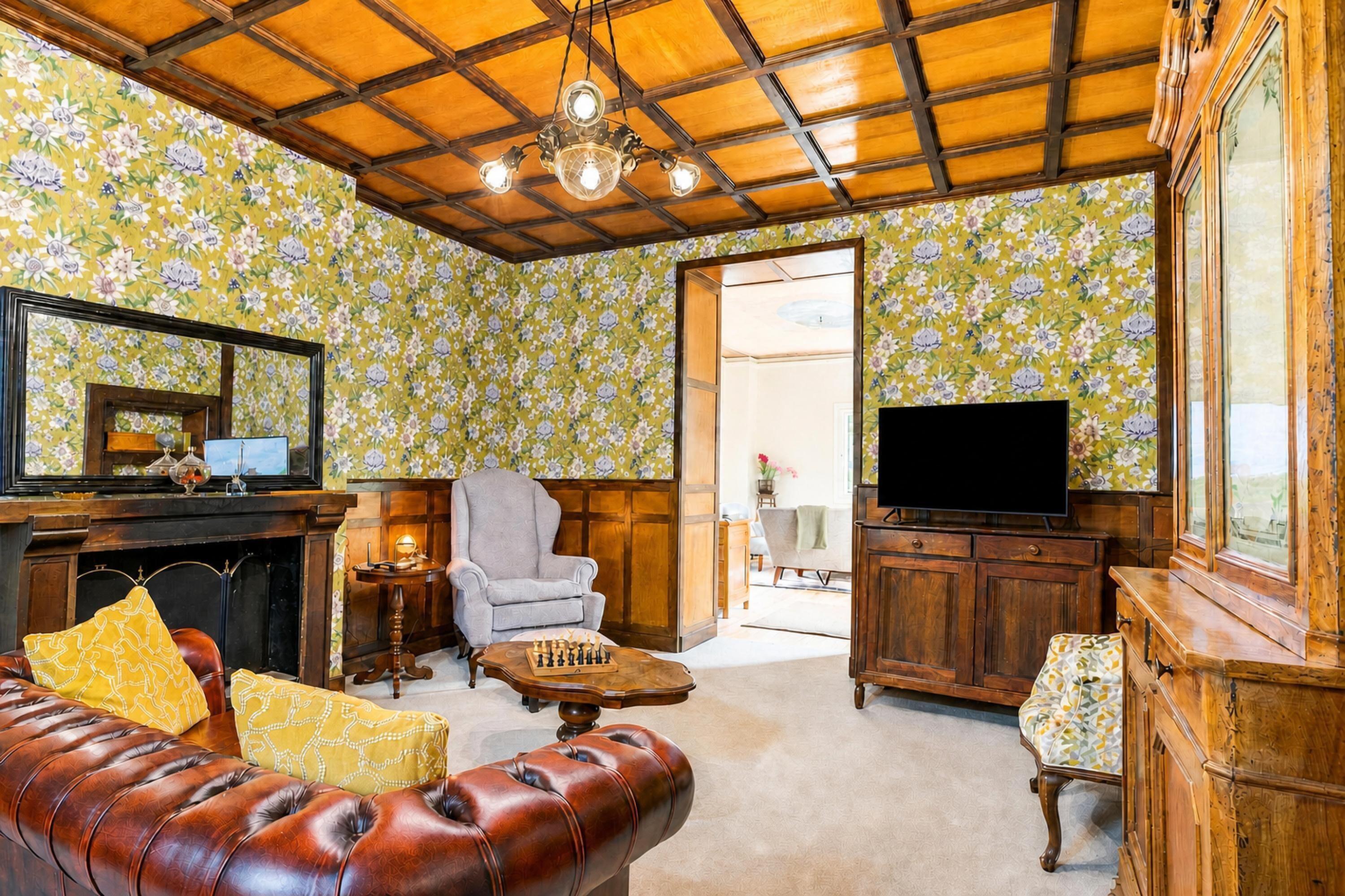 A living room with a fireplace, a television, a sofa, and a chess table.