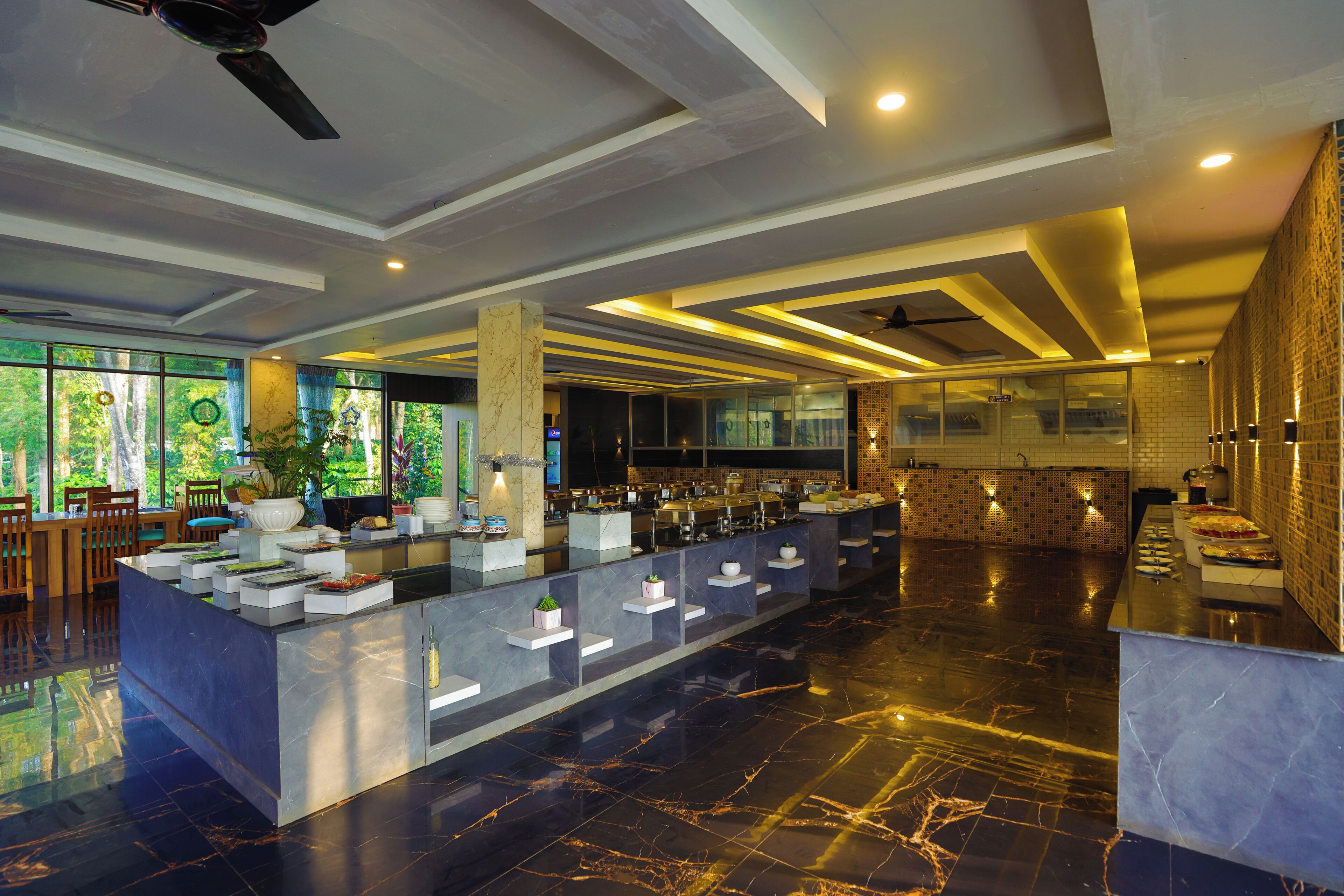 En moderne hotellobby med en bordplade i marmor ved receptionen, siddeområde og store vinduer med udsigt til grønne områder.