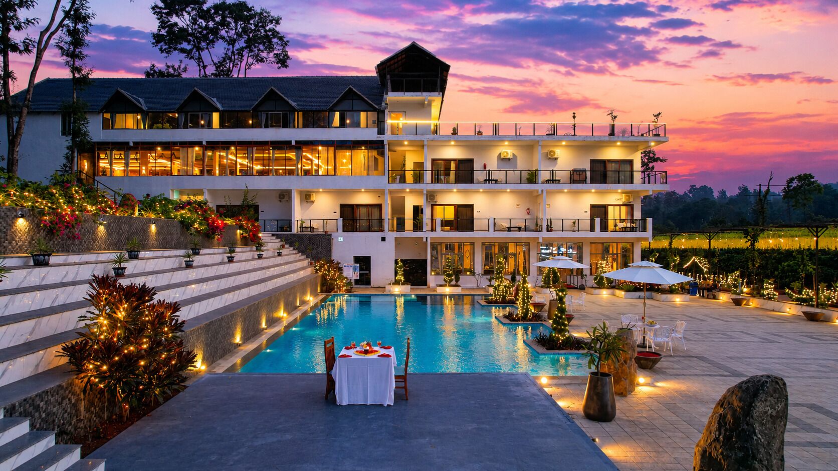 A hotel with a pool, outdoor seating, and a large building with multiple floors and balconies.
