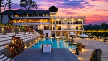 A hotel with a pool, outdoor seating, and a large building with multiple floors and balconies.