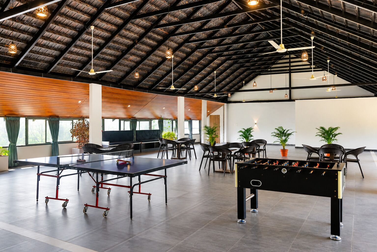 A spacious indoor area with a ping pong table, a foosball table, and multiple seating arrangements.