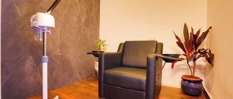 A room with a black leather chair, a white desk lamp, and two potted plants.