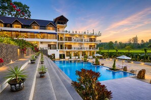 Ein mehrstöckiges Hotel mit Schwimmbad, Außenbereich und Garten.