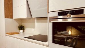 Een moderne keuken met witte kasten, een inbouwoven en een digitaal bedieningspaneel.