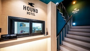 En reception med skilt for HOUND HOTEL, en nøgleboks og en trappe.