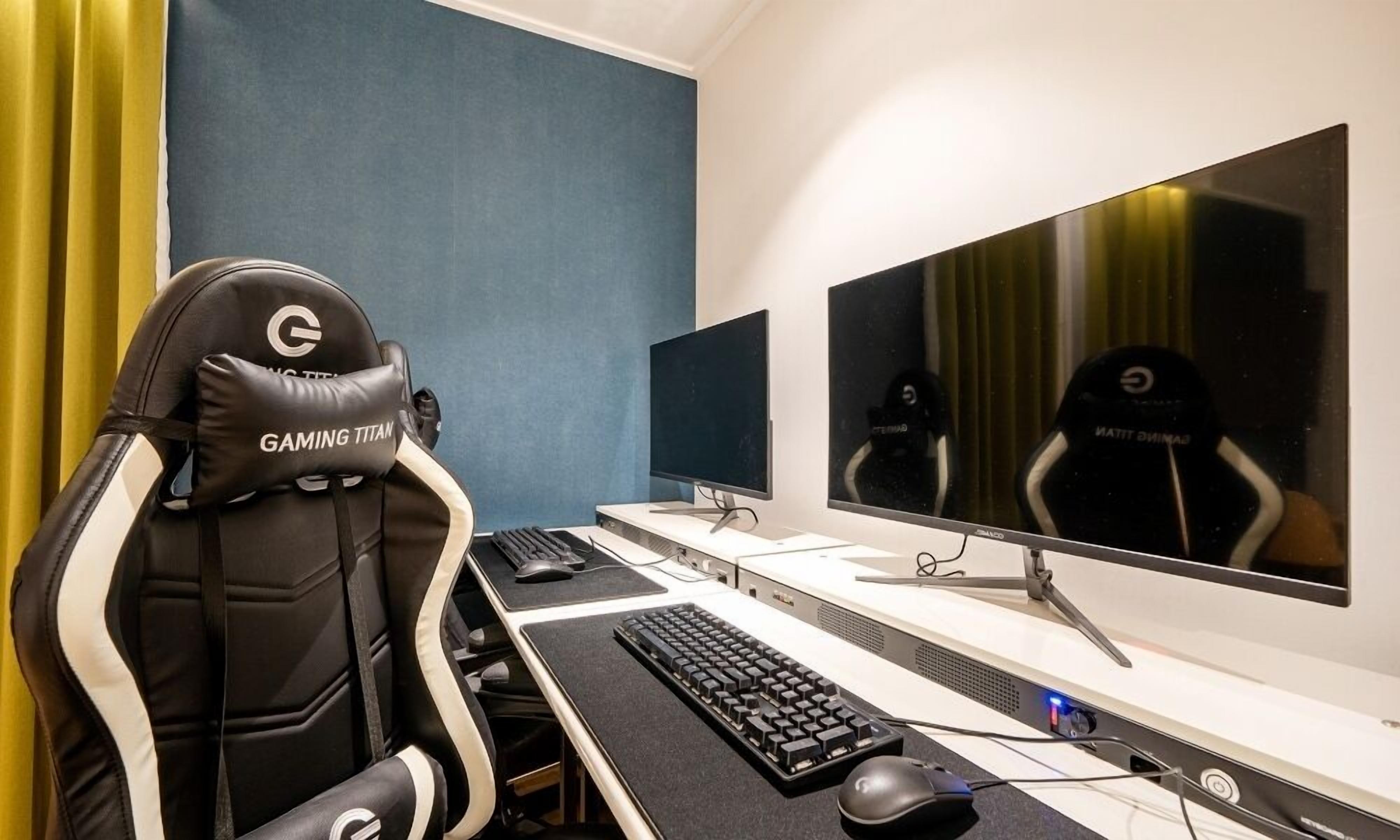 Uma cadeira gamer com a marca 'GAMING TITAN', configuração de dois monitores, teclado e mouse em uma mesa.