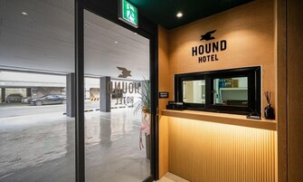 A reception desk at Hound Hotel with a wooden finish and a sign above it.