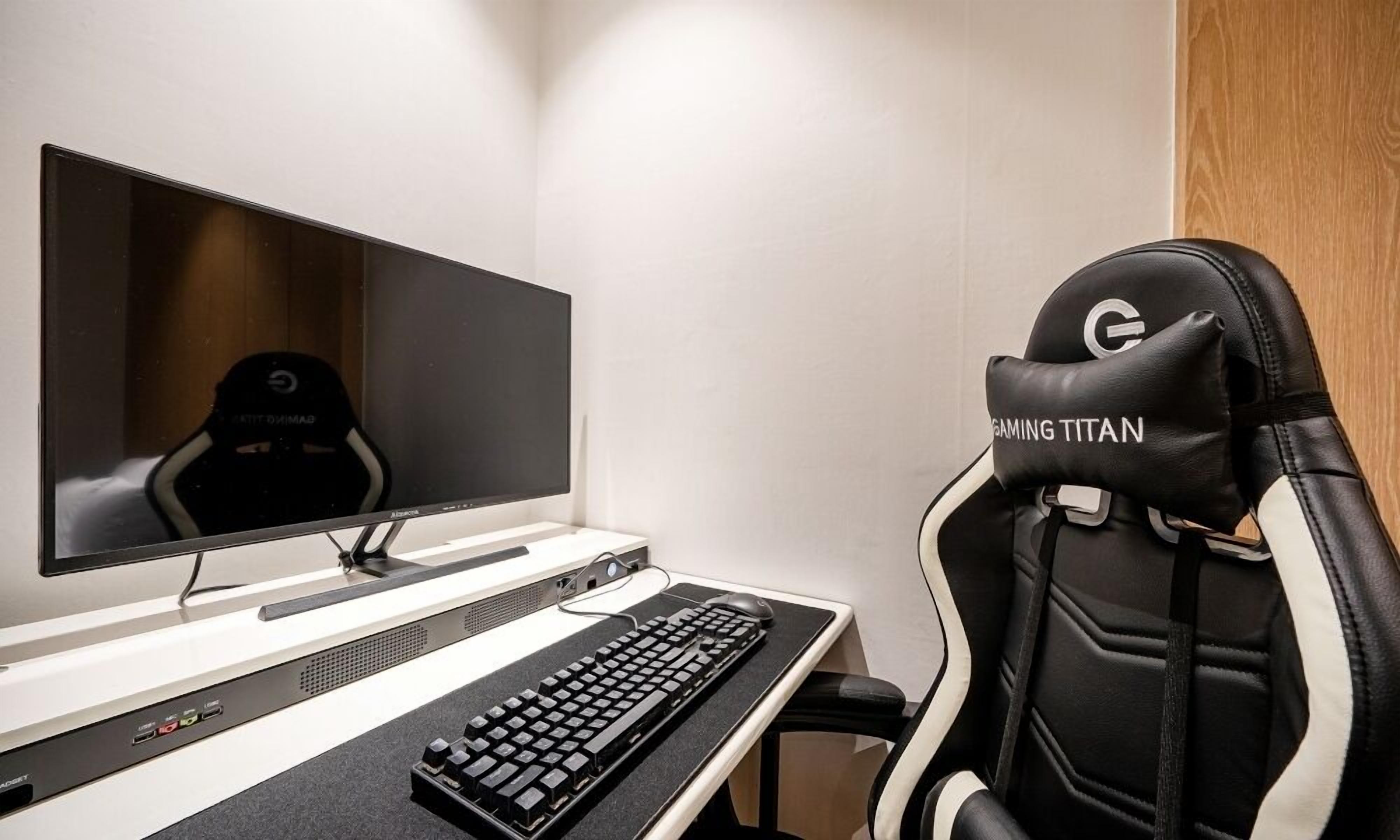A gaming chair with a logo, a monitor, a keyboard, and a gaming mouse on a desk.