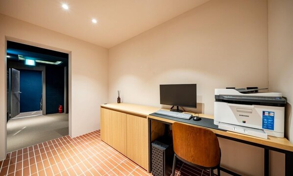Un espacio de oficina moderno con escritorio, computadora, impresora y silla.