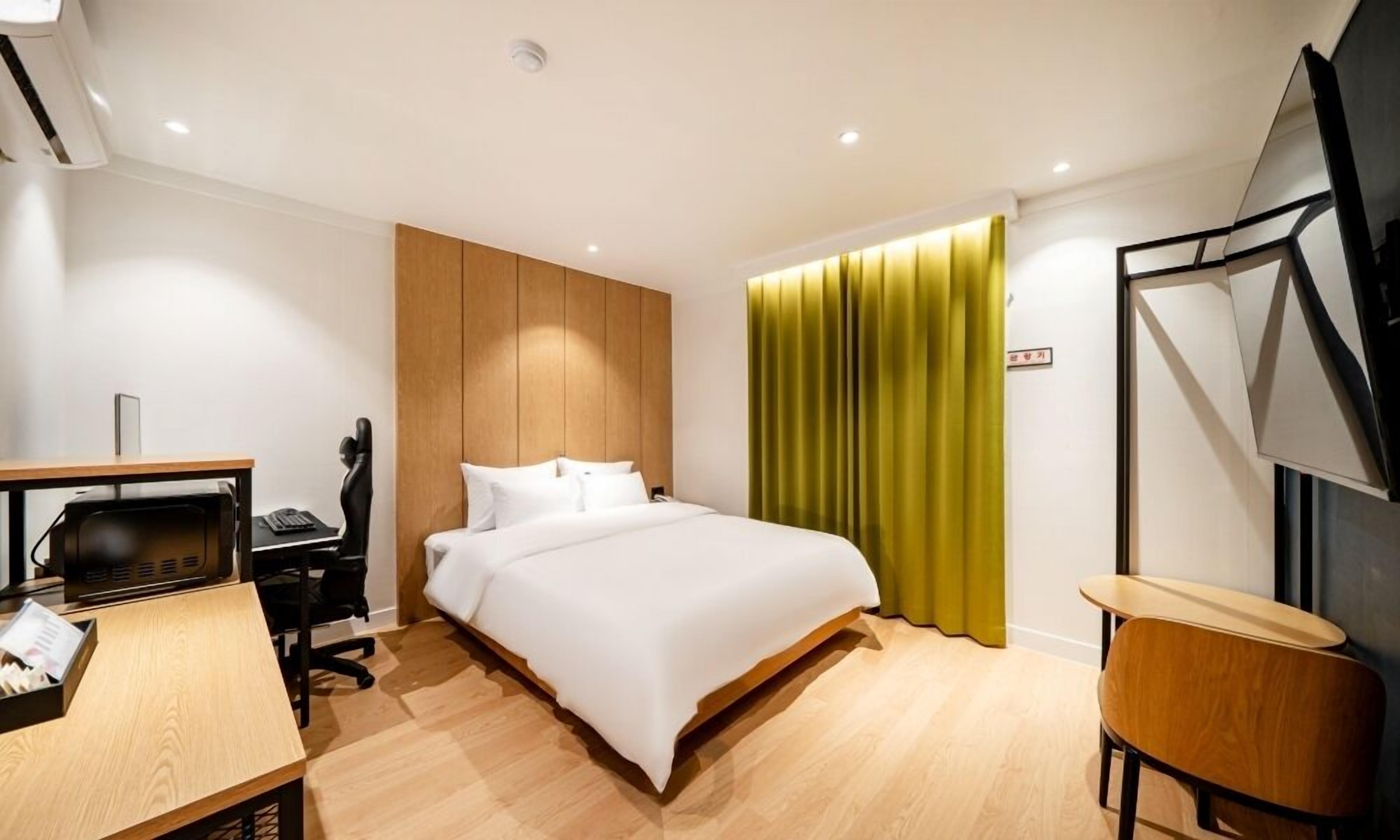 Una habitación de hotel con cama, escritorio, silla y televisor.