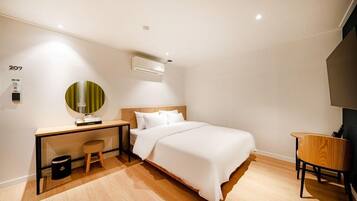 Una habitación de hotel moderna con cama, escritorio, silla y un taburete pequeño.