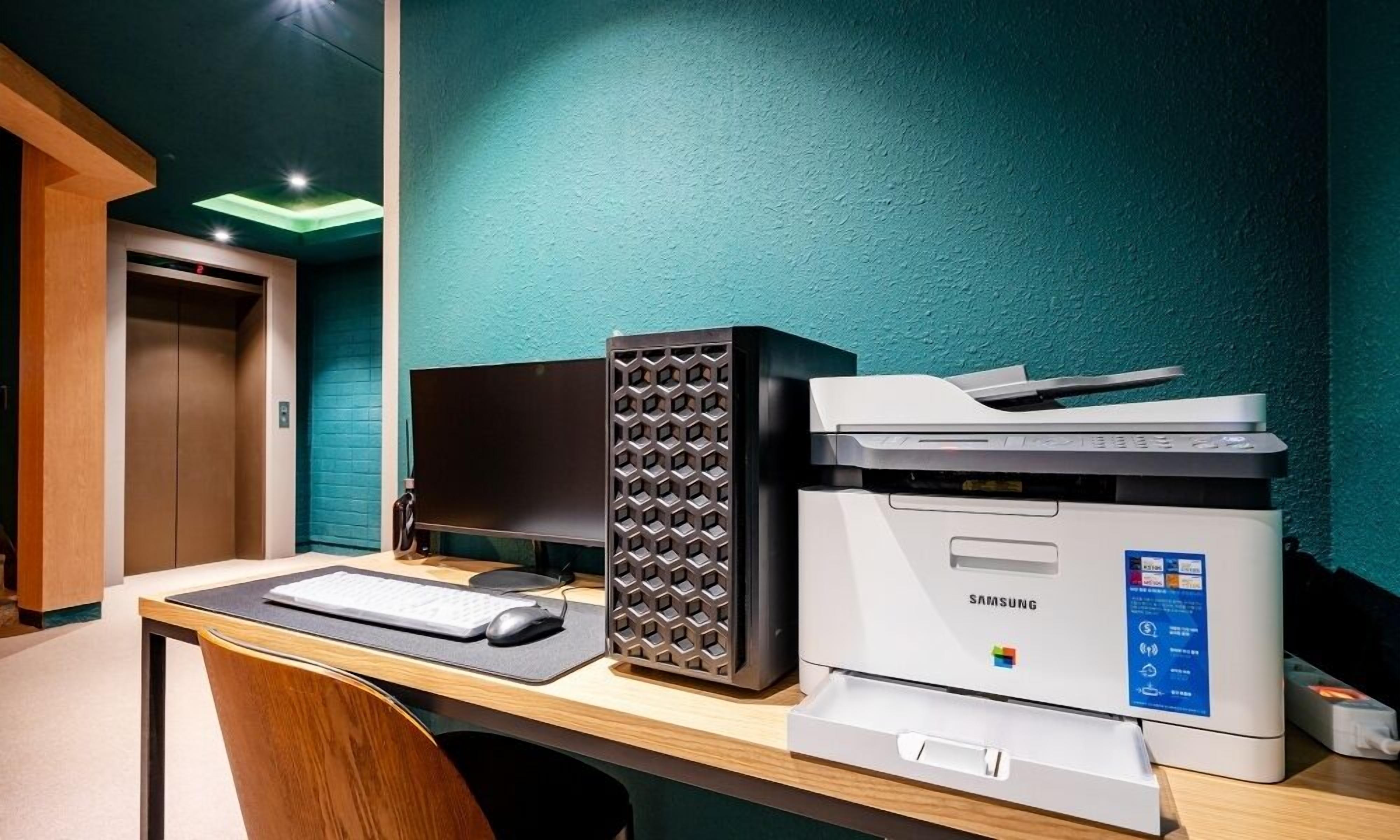 Un escritorio con un monitor de computadora, una impresora y un teclado.