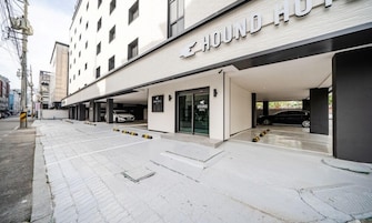 A modern building with a 'HOUND HOTEL' sign, covered parking, and a clean, paved walkway.