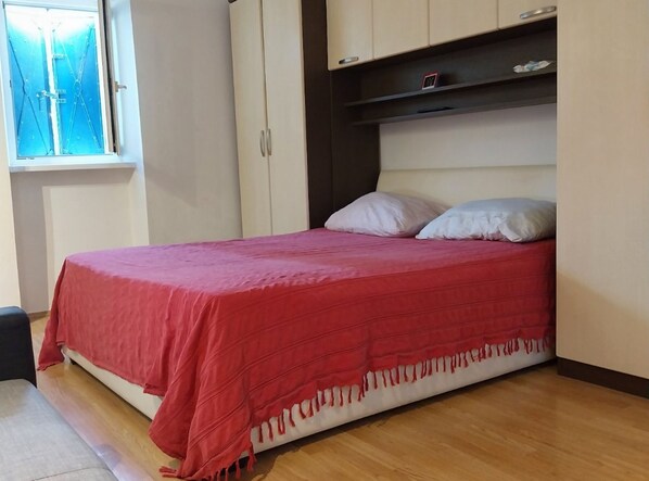 Un dormitorio con cama, ventana y armario.