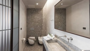 Un baño moderno con lavamanos de mármol, un bidé y un espejo grande.