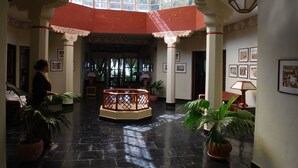 A spacious lobby with a central seating area, a high ceiling with a skylight, and framed artwork on the walls. - Norling House (Dharamshala)