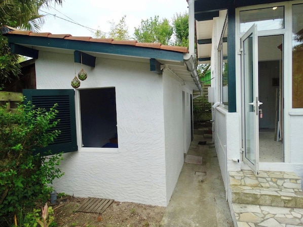 A white building with a tiled roof, a small window, and a door leading to an interior space.